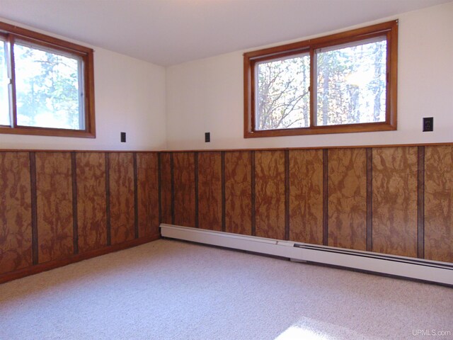 spare room with a baseboard heating unit and light colored carpet