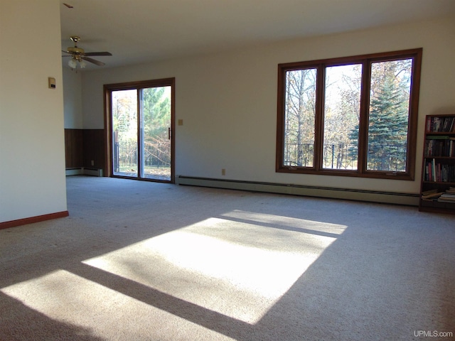 unfurnished living room with a baseboard heating unit, carpet flooring, and ceiling fan