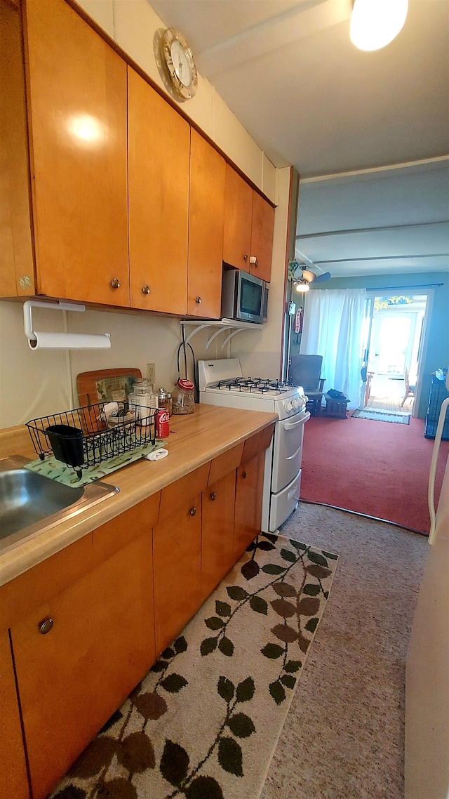 kitchen featuring ceiling fan, white gas range oven, and light colored carpet