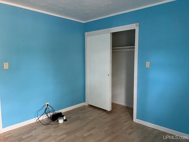 unfurnished bedroom with a closet, light hardwood / wood-style floors, and crown molding