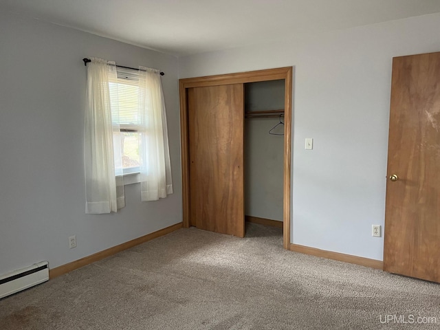 unfurnished bedroom with baseboard heating, carpet, and a closet