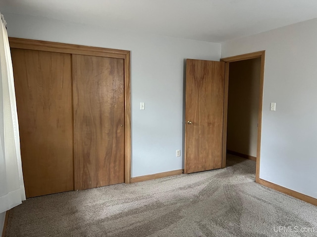 unfurnished bedroom featuring light colored carpet and a closet