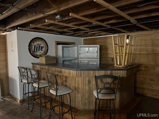 bar featuring dark tile patterned floors and wood walls