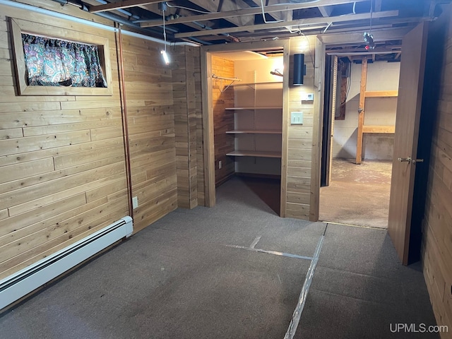 basement featuring wood walls and a baseboard radiator