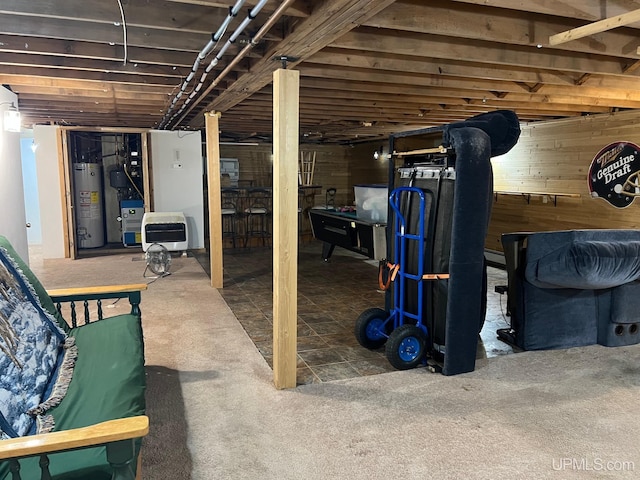 basement featuring wooden walls, carpet, and water heater