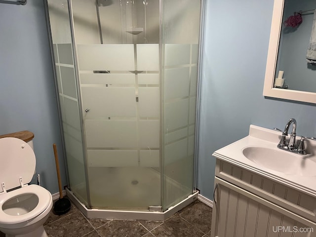 bathroom with a shower with door, vanity, toilet, and tile patterned flooring