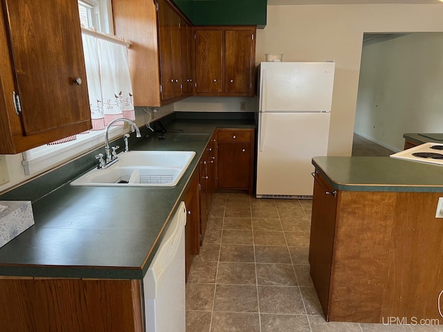 kitchen featuring dark tile patterned flooring, sink, and white appliances