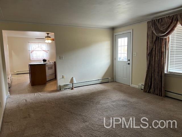 empty room with a wealth of natural light, ornamental molding, a baseboard heating unit, and light carpet