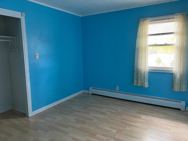 unfurnished bedroom with ornamental molding, a closet, a baseboard heating unit, and light wood-type flooring