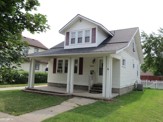 view of front facade with a porch, a front lawn, and central AC unit