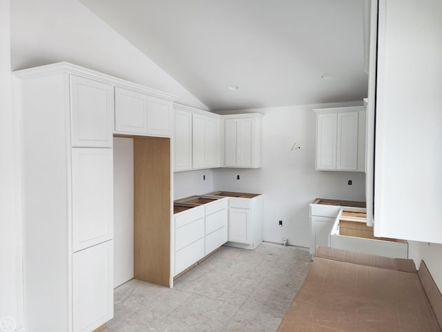 kitchen featuring vaulted ceiling and white cabinetry