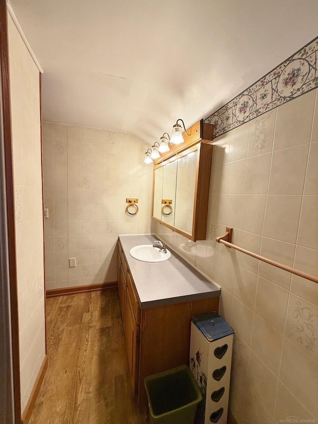 bathroom featuring vanity, hardwood / wood-style flooring, tile walls, and lofted ceiling