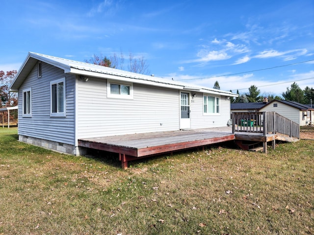 rear view of property featuring a wooden deck and a lawn