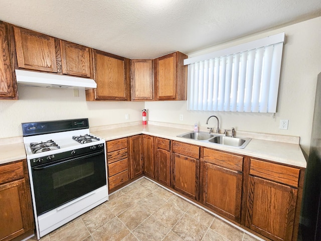 kitchen with a textured ceiling, white gas stove, and sink