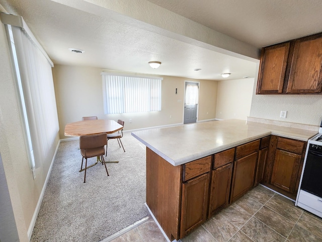 kitchen with kitchen peninsula, a textured ceiling, white range, and carpet flooring