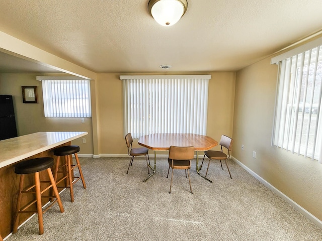 dining space featuring light carpet and a textured ceiling