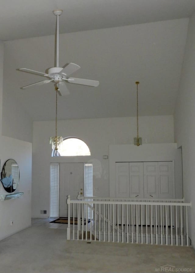 carpeted spare room with high vaulted ceiling and ceiling fan with notable chandelier