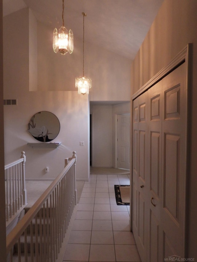 hall featuring a notable chandelier, high vaulted ceiling, and light tile patterned floors