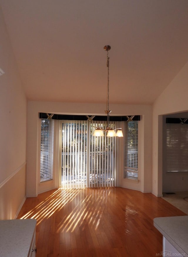 unfurnished dining area with lofted ceiling and hardwood / wood-style floors