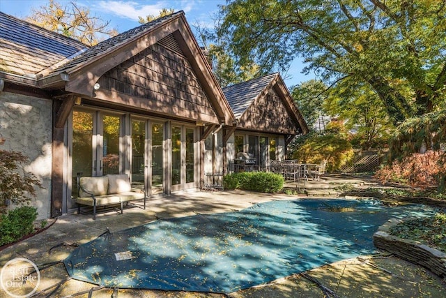 back of property featuring a covered pool and a patio