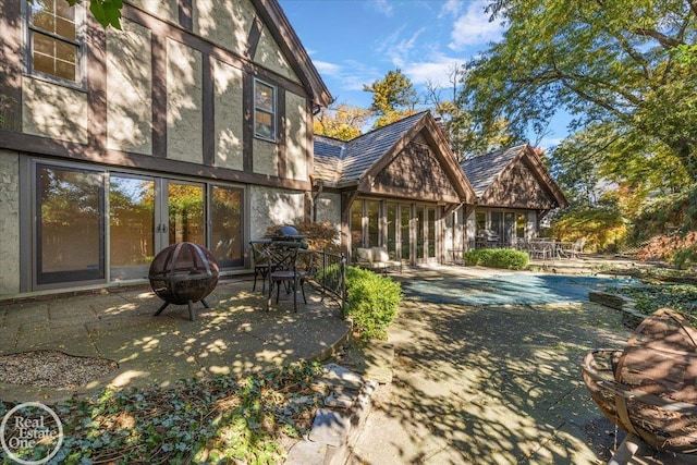 back of house featuring an outdoor fire pit, a pool, and a patio