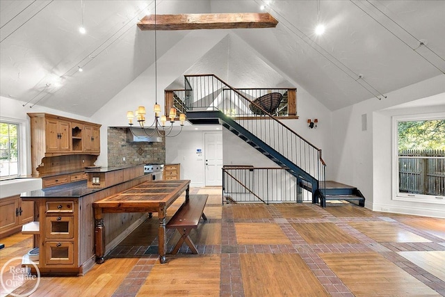 kitchen with light tile patterned floors, pendant lighting, tasteful backsplash, and high vaulted ceiling