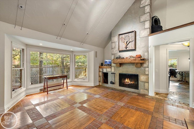 unfurnished living room featuring high vaulted ceiling and a stone fireplace