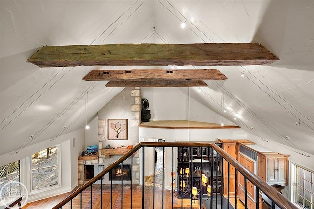 additional living space featuring lofted ceiling with beams, a fireplace, and hardwood / wood-style flooring