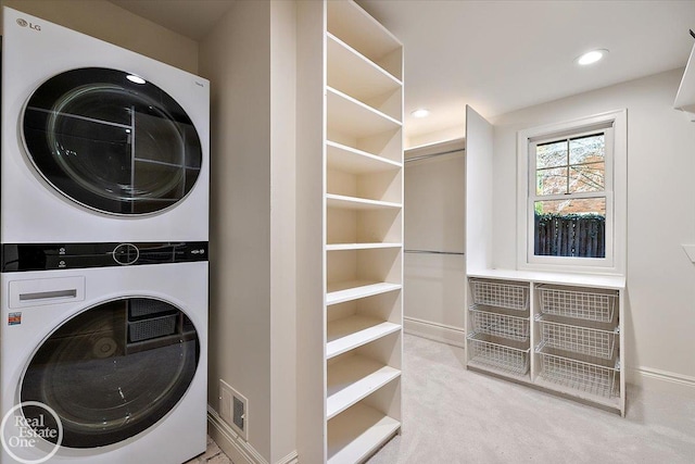 washroom featuring stacked washer and clothes dryer and light carpet