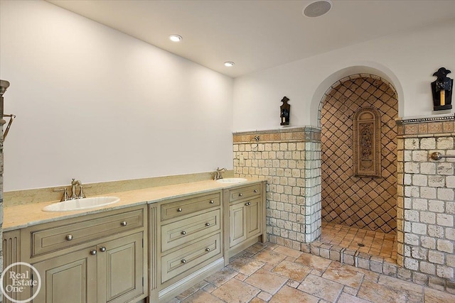 bathroom featuring tile walls, tiled shower, and vanity