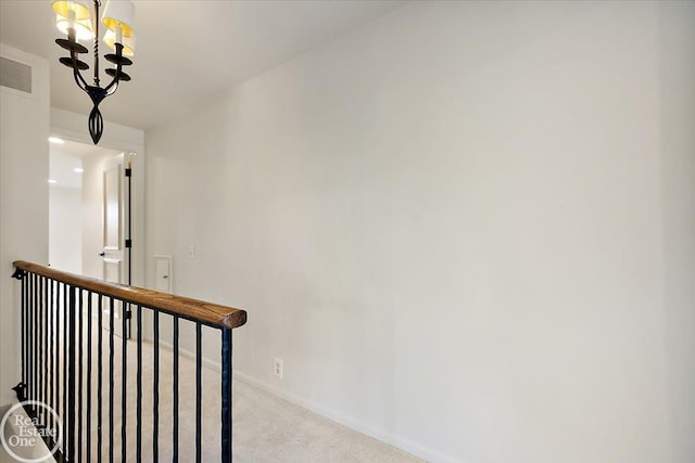 hall featuring light colored carpet and a notable chandelier