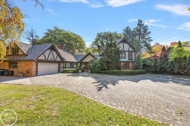 17680 E Jefferson Ave, Grosse Pointe, MI 48230 - tudor home with brick siding, decorative driveway, a garage, a front lawn, and a chimney