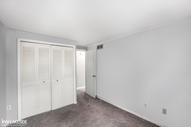 unfurnished bedroom featuring dark carpet and a closet