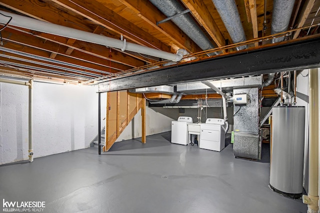 basement featuring washing machine and clothes dryer, sink, heating unit, and gas water heater