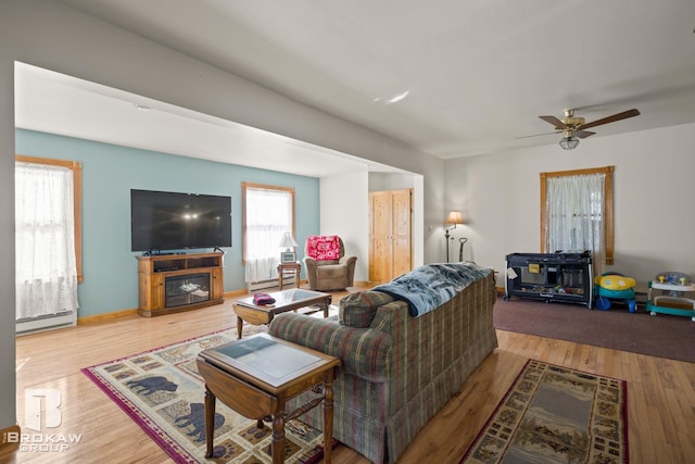 living room featuring a baseboard heating unit, light wood-type flooring, and ceiling fan