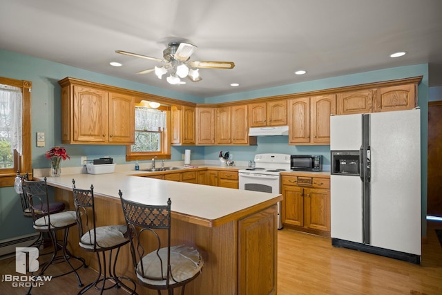 kitchen with light hardwood / wood-style floors, kitchen peninsula, a kitchen bar, and white appliances