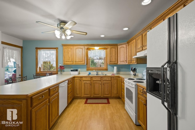 kitchen with white appliances, light wood-type flooring, sink, and kitchen peninsula