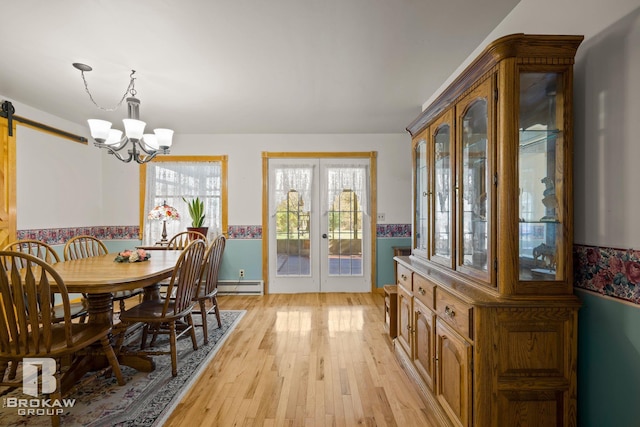 dining space featuring a baseboard heating unit, a barn door, french doors, light hardwood / wood-style floors, and an inviting chandelier