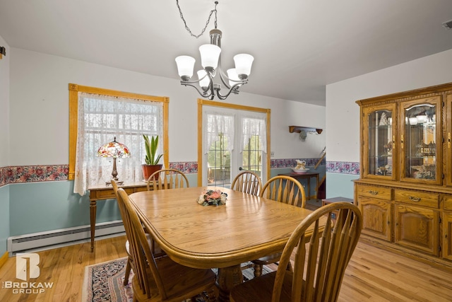 dining room with light hardwood / wood-style floors, a baseboard heating unit, and a chandelier