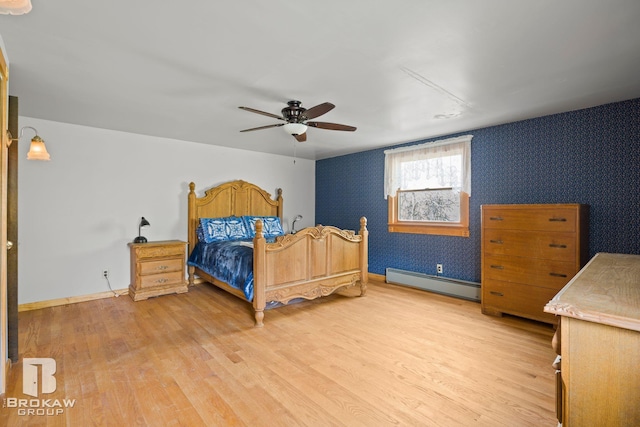 bedroom with a baseboard heating unit, light wood-type flooring, and ceiling fan