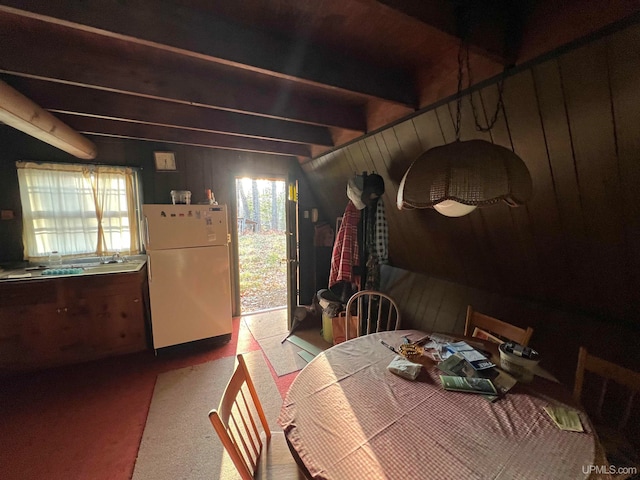 dining area featuring wood walls and beam ceiling