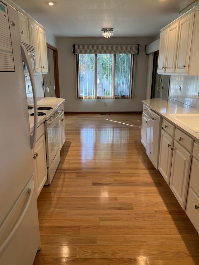 kitchen featuring white cabinets, light wood-type flooring, and white appliances