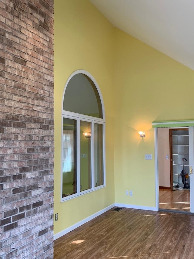 empty room with high vaulted ceiling and dark hardwood / wood-style floors