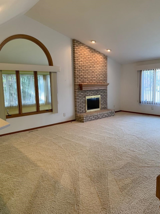 unfurnished living room with a fireplace, lofted ceiling, and carpet floors