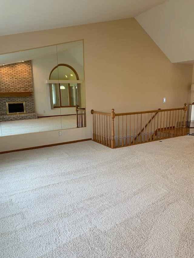 unfurnished living room with a fireplace, carpet floors, and lofted ceiling