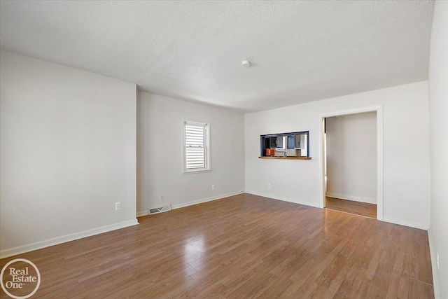 unfurnished room featuring hardwood / wood-style floors and a textured ceiling