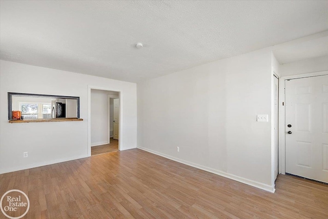 empty room with light hardwood / wood-style flooring and a textured ceiling