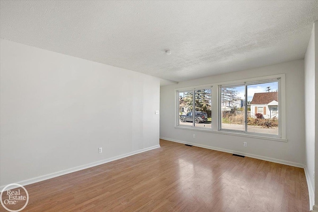 empty room featuring a textured ceiling and light wood-type flooring