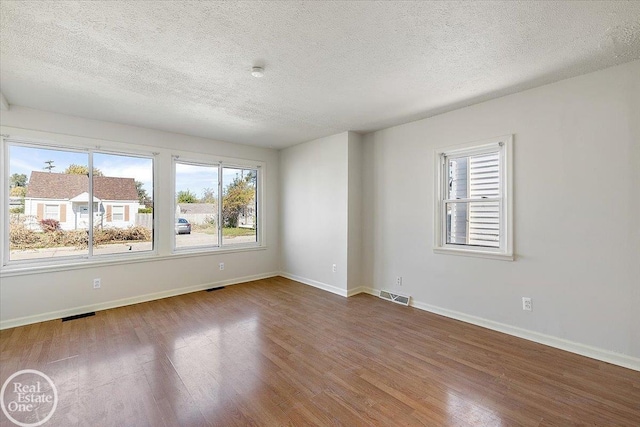 empty room featuring a textured ceiling and wood-type flooring