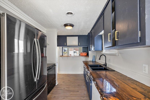 kitchen featuring black appliances, dark wood-type flooring, crown molding, wooden counters, and sink